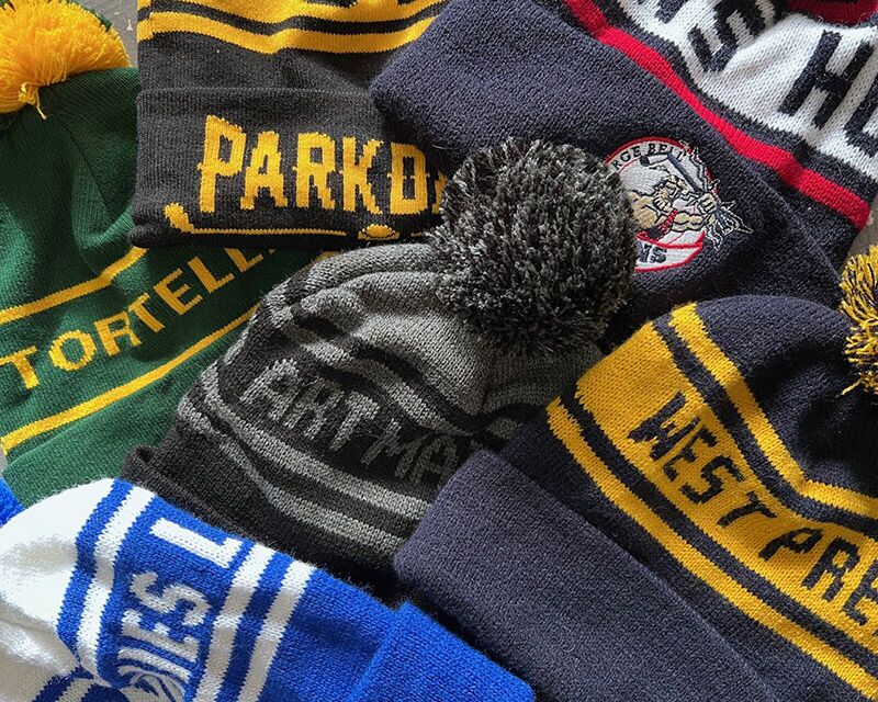A selection of toques that have been custom knit with design and logos.