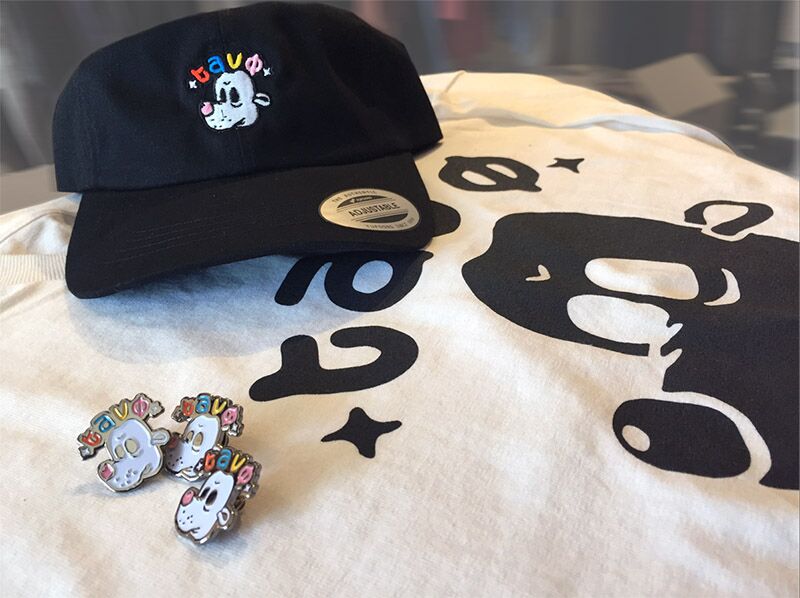 A cap, t-shirt, and enamel pins with personal branding.